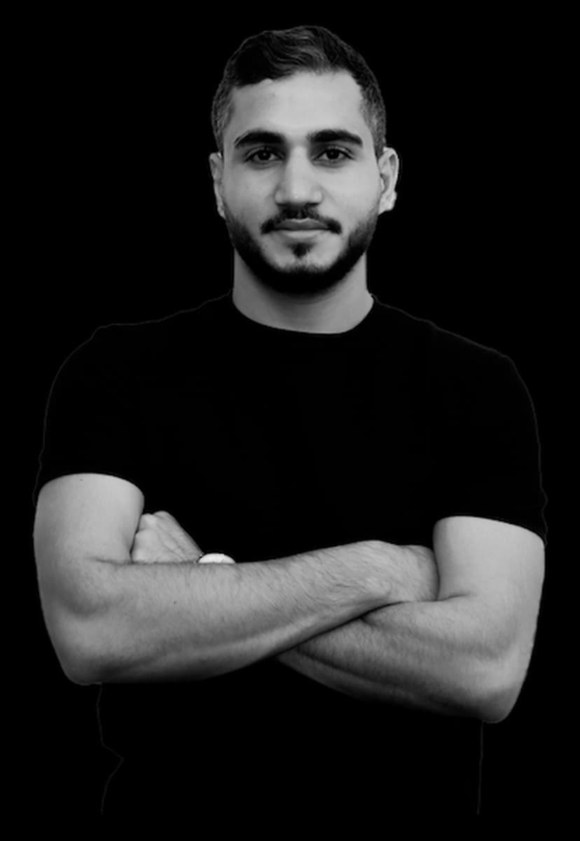 Black-and-white portrait of Abdul, arms crossed, wearing a black t-shirt.